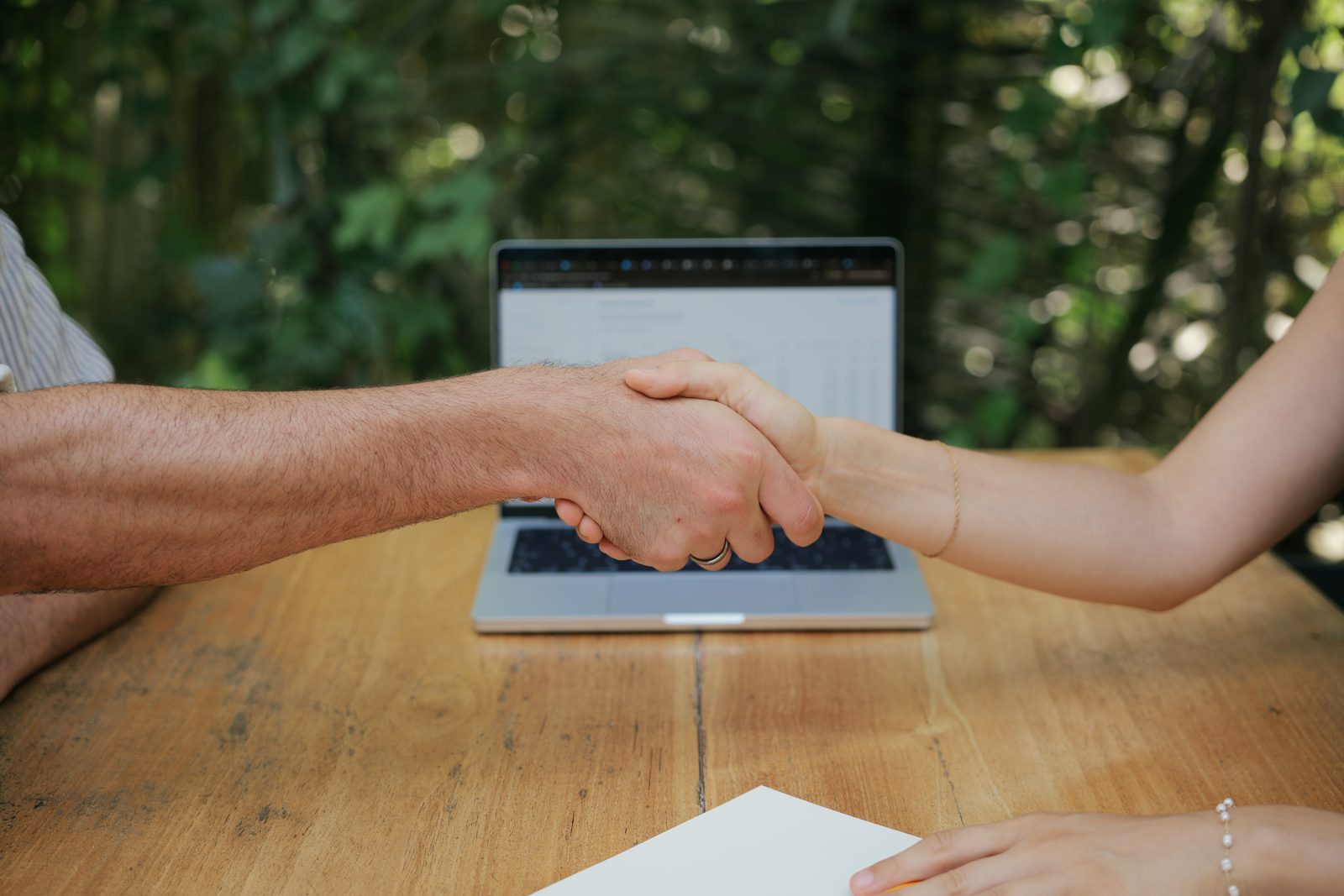 A handshake across the table in front of a laptop — the True Tally accountability partnership